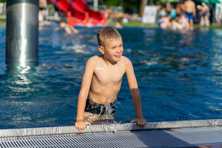 Smiling boy having fun and active summer leisure time in the outdoor poolの写真素材