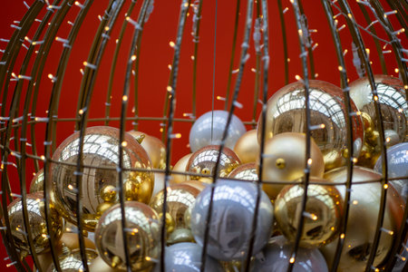 Close-up of shiny gold and silver Christmas ornaments with string lights on red festive backgroundの写真素材