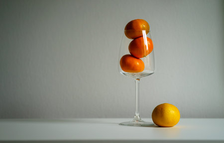 Fresh ripe orange tangerines in and near a glass wine glass on a white background.の写真素材