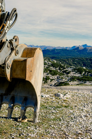 The bucket of a heavy excavator before the start of construction work on the top of a mountain against the backdrop of natureの写真素材