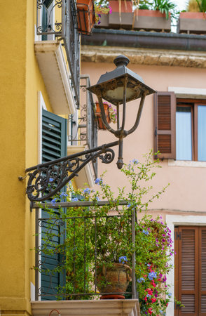 Nice authentic balcony decorated with flowers in a clay pot and a small street lamp in an ancient Italian buildingの写真素材