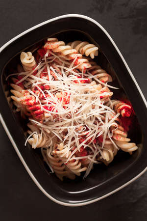 Italian pasta with cheese. Macaroni with spices. Red pepper. Parmesan with pasta. Pasta in a black plateの写真素材