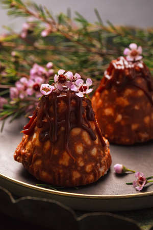 Chocolate brownies with nuts and cookie slices and sweet caramel with pink little flowers in vintage...