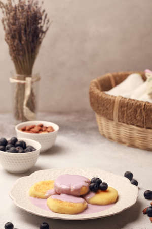 Breakfast of pancakes and yoghurt. Fresh berries and nuts. Blueberries with almonds. Cheesecakes with blueberries and yogurt. Light background. Purple and whiteの写真素材
