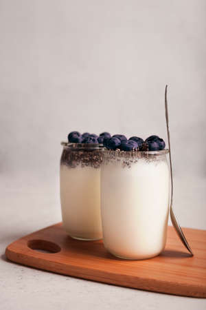 Yogurt with blueberries and Chia. Fresh healthy breakfast. Light background. White Greek yogurt in jarsの写真素材