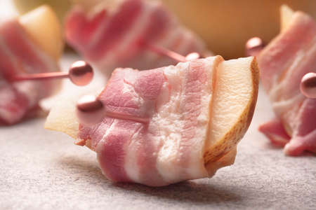 Pink thin slices of bacon on skewers in a pear with soft cheese will complement any healthy snack and buffet tableの写真素材