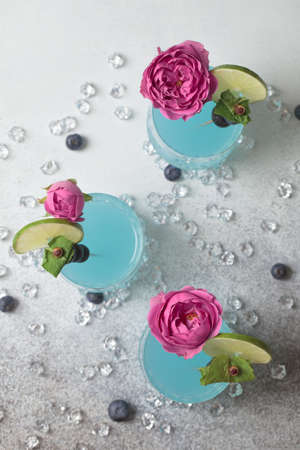 Blue soda. Ice blue cocktail glass. Blue Hawaiian cocktail on a white plate with lime. Blue curacao cocktail. Blue drink with fruit garnishの写真素材