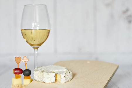 Glass of white wine, canapes and camembert cheese on a wooden background - horizontalの写真素材