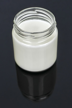 Goat milk yogurt in glass jar on a black background - verticalの写真素材