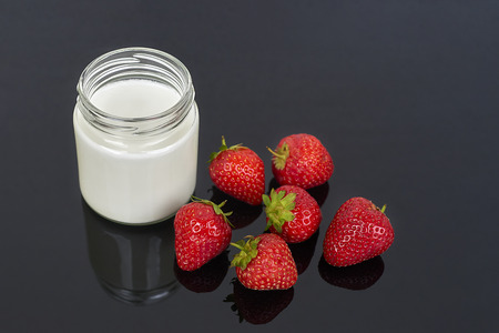 Yogurt in glass jar and strawberries on a black background - horizontalの写真素材