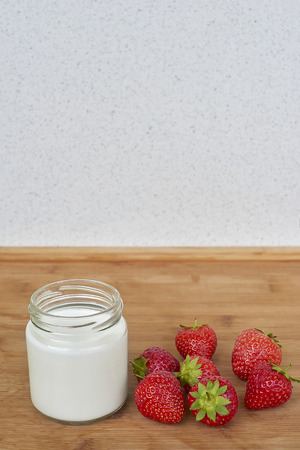 Yogurt in glass jar and strawberries on a wood background - verticalの写真素材
