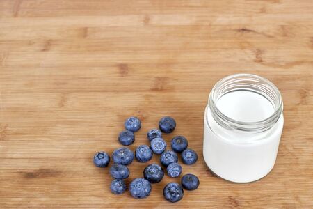 Yogurt in glass jar and blueberries on a wooden background - mock up templateの写真素材