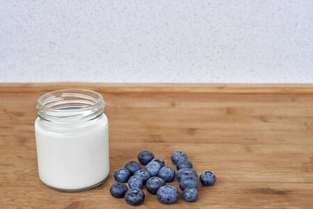 Yogurt in glass jar and blueberries on a wooden background - horizontalの写真素材