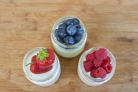Three glass jars with yogurt and forest berries - directly aboveの写真素材