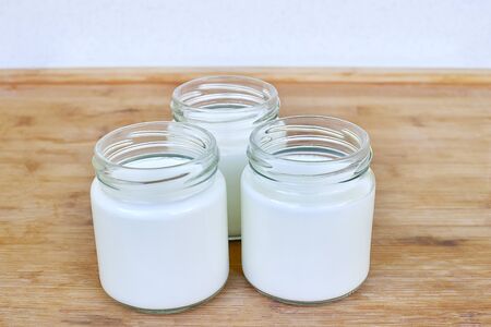 Three glass jars with yogurt on a wooden background - close upの写真素材