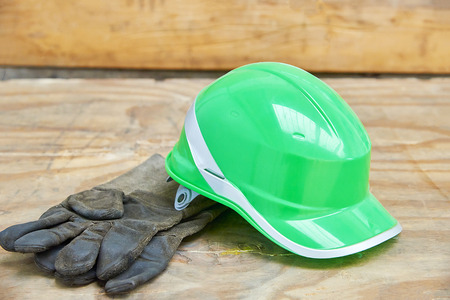 Green safety helmet and gauntlet cloves on a wooden backgroundの写真素材