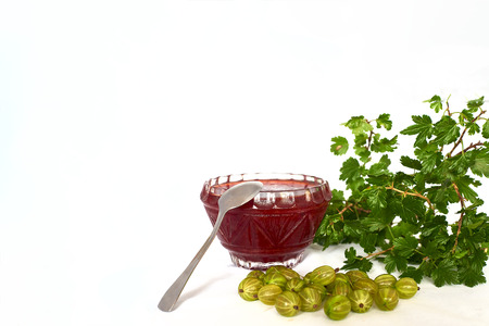 Gooseberries, jam with tea spoon and twig with green leavesの写真素材