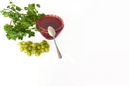 Gooseberries, jam with tea spoon and twig with green leaves