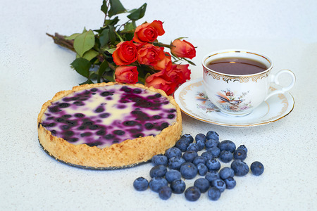 Blueberry pie, cup of tea, heap of blueberries and red roses on a white background - still life foodの写真素材