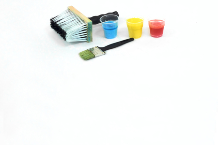 Big and small paintbrushes and blue, yellow and red stains