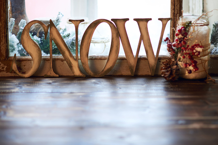 Word SNOW - wooden letters and candle holder decorated with pine cone and ashberry on windowsillの写真素材