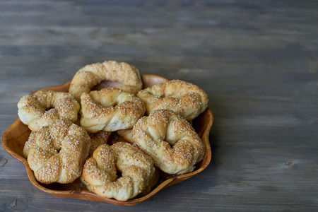 Delicious and sweet braided wicker pastry with sesame seeds on a wooden flower shaped plate on a...