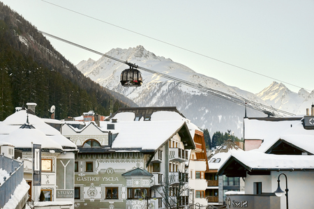 Ischgl, Austria - December 24, 2017: Modern aerial tramway in the Austrian Alps ski resort. Highland cable car leads between hills from village to ski slope. Cable car station in Ischgl city center. View from the city.のeditorial素材