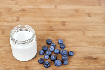 Glass jar with yogurt and blueberries on a wooden background horizontalの写真素材