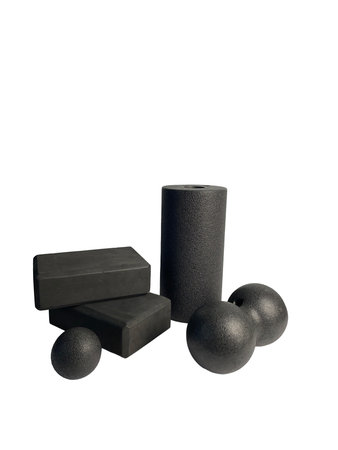 Black yoga blocks, a massage roller, and spherical massage balls sit against a white backdrop. The collection of equipment suggests a focus on muscle recovery and flexibility.の写真素材