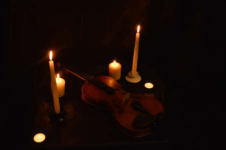 Group of burning candles and violin on black background.の写真素材
