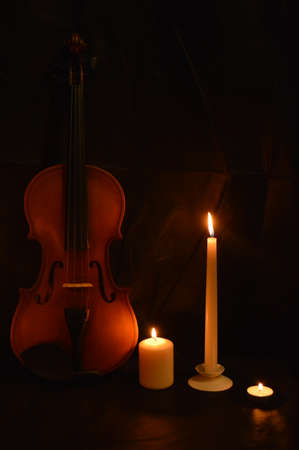 Group of burning candles and violin on black background.の写真素材