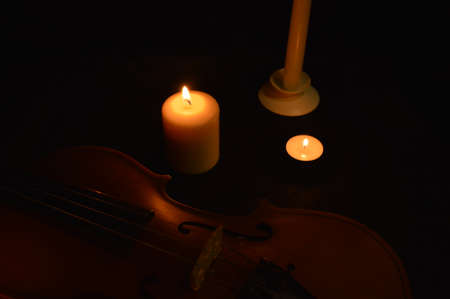 Group of burning candles and violin on black background.の写真素材