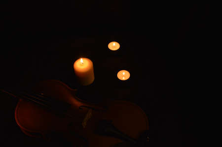 Group of burning candles and violin on black background.の写真素材