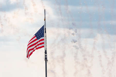 American flag waving in the wind in the sky with firework smoke