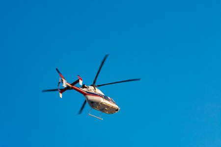 Helicopter flying high in the blue skyの写真素材