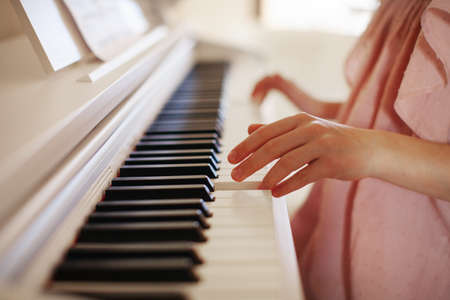 Close up girl hands playing piano keyboard. Blurred background