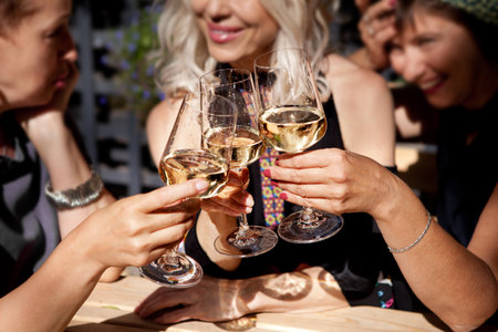 Women Clinking glasses with alcohol and toasting, party on summer terrace cafe or restaurant, celebrate holidayの写真素材