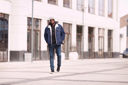 Serious modern fashion man in stylish denim clothes walks in urban street, full lengthの写真素材