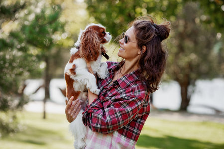 Woman pet owner affectionately holds her dog outdoors, love and bond with petの写真素材