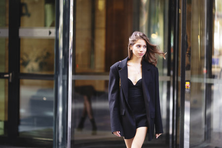 Person wearing elegant outfit with oversize black blazer, Walking in urban setting. Modern fashion, street styleの写真素材