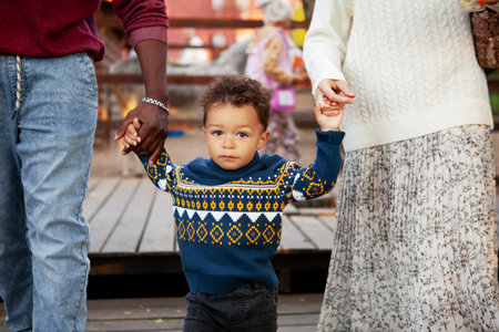 Young Child Boy Walks Hand In Hand With Parents Outdoors in Park, Looking At Camera. Family outingの写真素材
