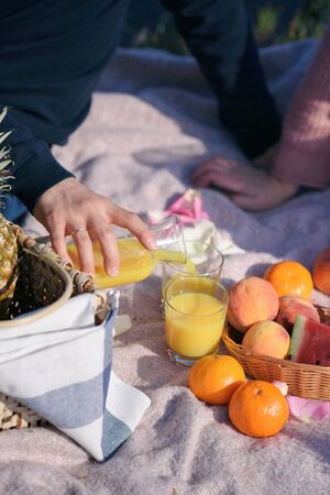 a man pours juice in a glass. Fruit on a picnic. weddingの写真素材