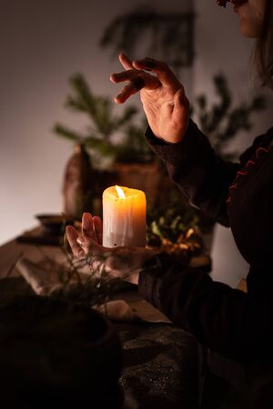 woman in the image of a witch in an old dress holding a burning candle in her handsの写真素材