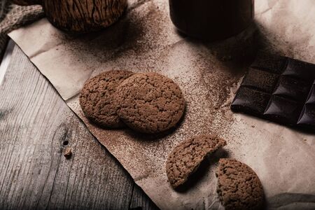 rustic, dark and blurry background. grain. On the table is a jar of chocolate nut paste, a mug and...
