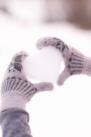 valentine's day concept. Heart made of snow in the hands of a girl.の写真素材