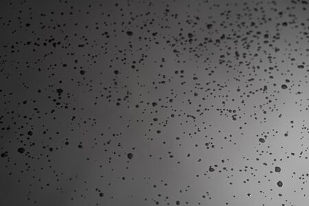 drops of water on black reflective glassの写真素材