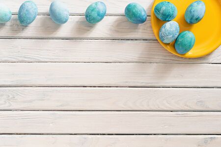blue marble eggs lie on a white background in a yellow plate, as a symbol of Easter