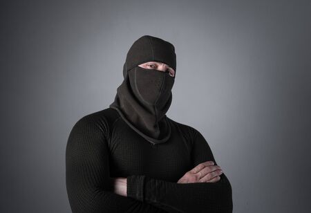 A man in a balaclava, as a concept of special forces or extremist clothes, stands with a sly lookの写真素材