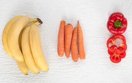 on a white background lie bananas, carrots and sweet peppersの写真素材