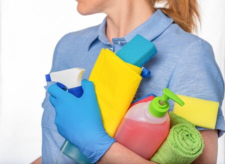 woman cleaner, in blue uniform and gloves, contains liquid cleaning products and sponges.の写真素材